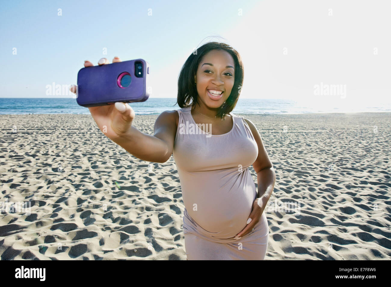 Pregnant woman taking cell phone picture on beach Stock Photo