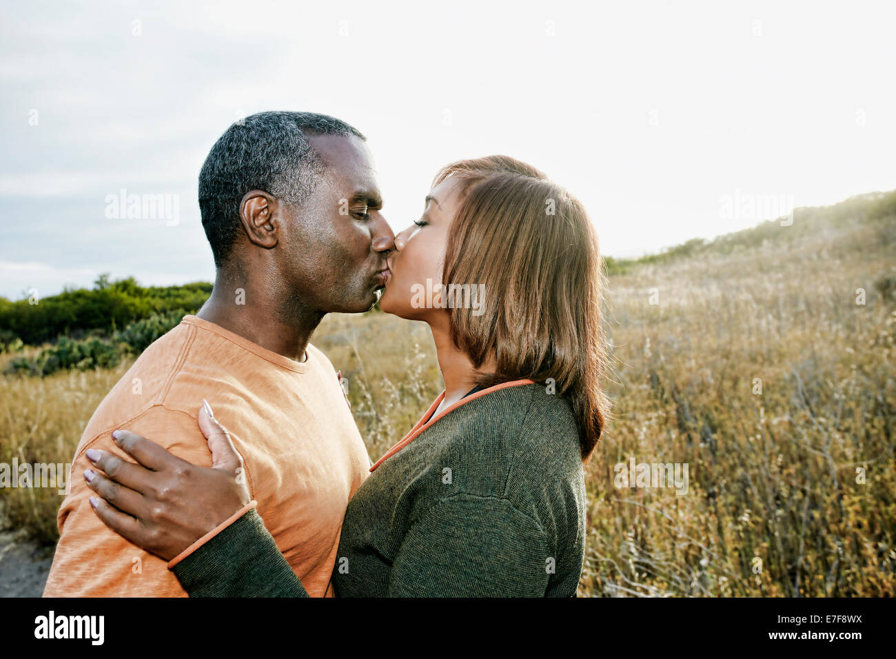 Black couple kissing on rural path Stock Photo