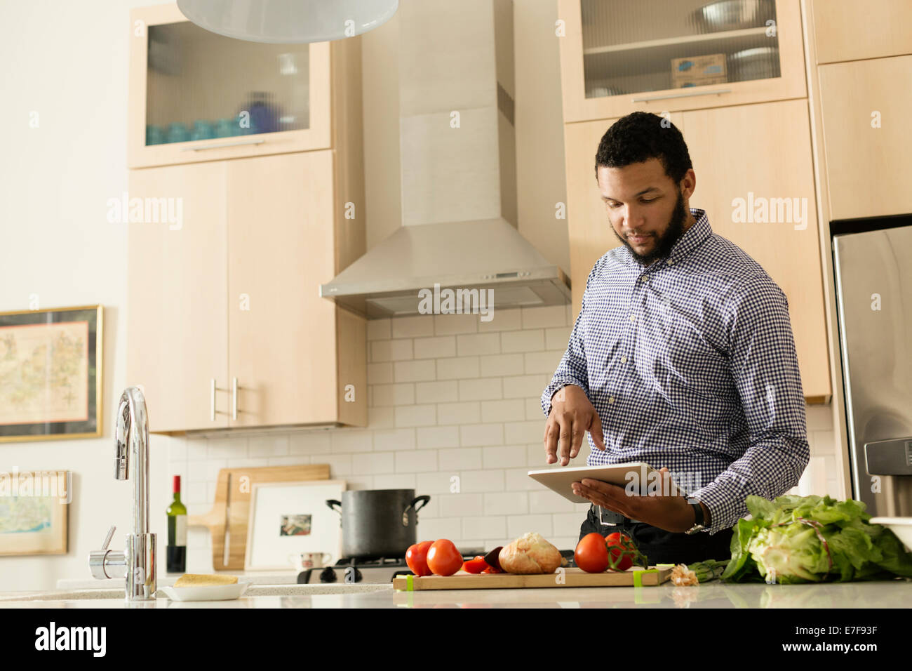 Mixed race man cooking with tablet computer in kitchen Stock Photo