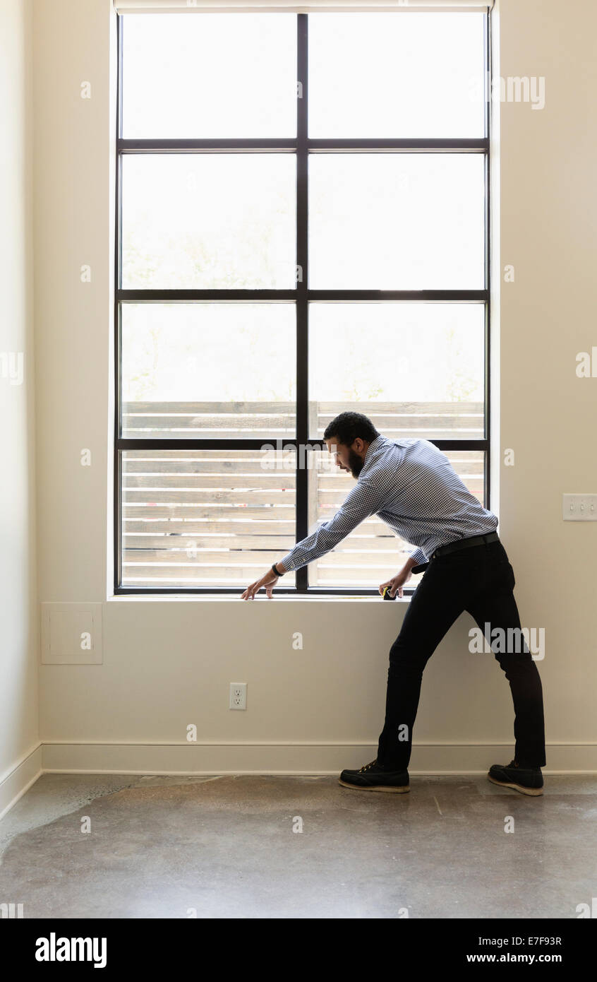 Mixed race realtor measuring window in new house Stock Photo