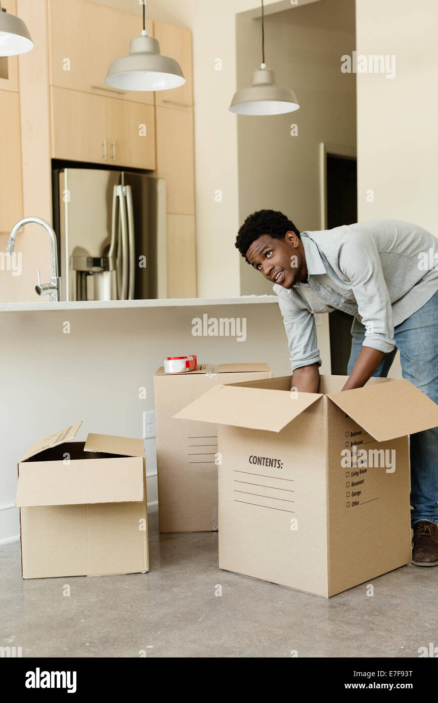 Black man unpacking cardboard box in new house Stock Photo