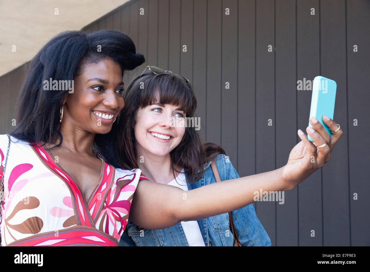 Women taking cell phone picture together outdoors Stock Photo