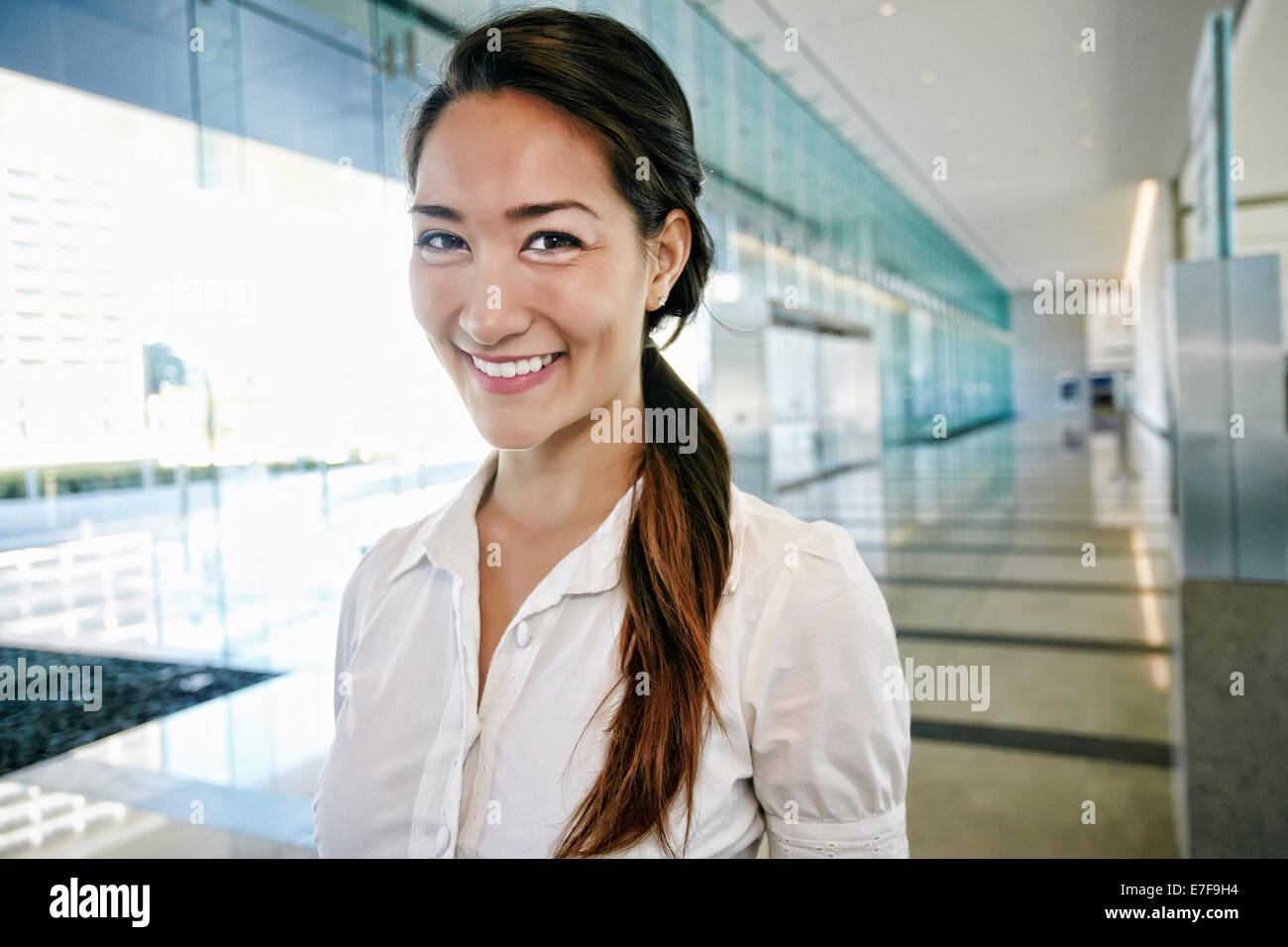 Mixed race businesswoman smiling in lobby Stock Photo