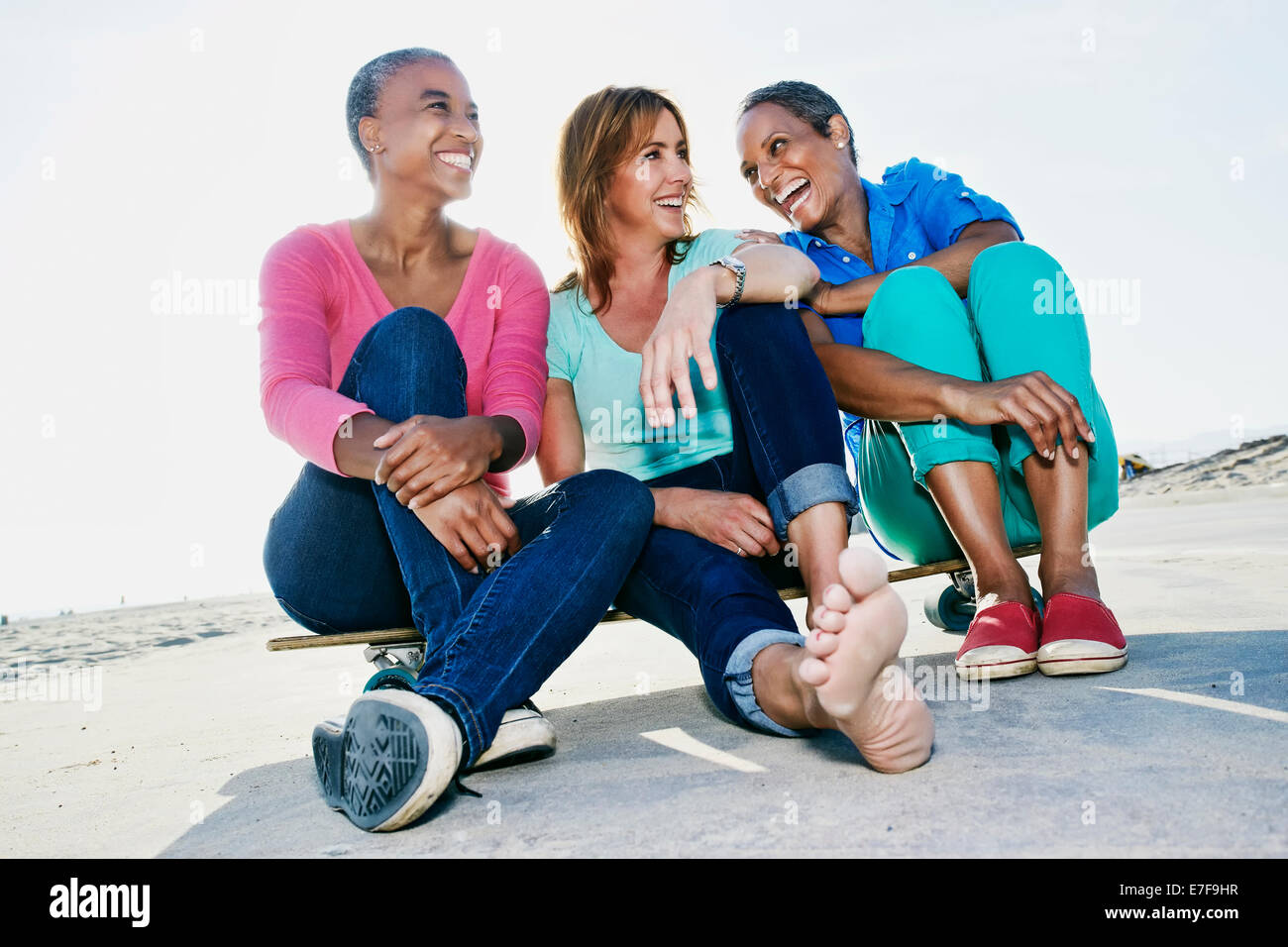 Older women sitting on skateboard on beach Stock Photo