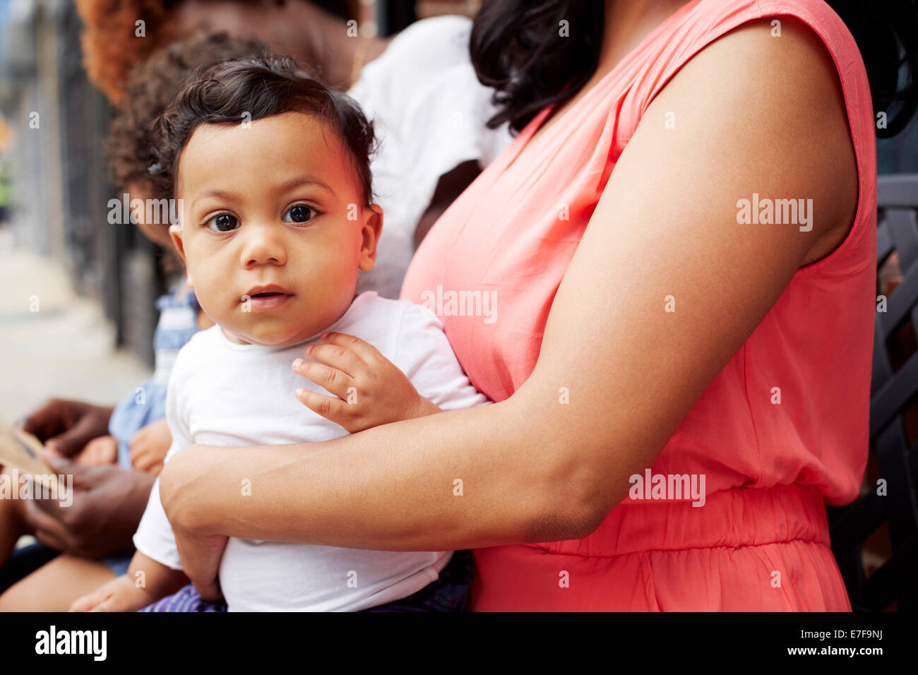 Mother holding toddler son on lap outdoors Stock Photo