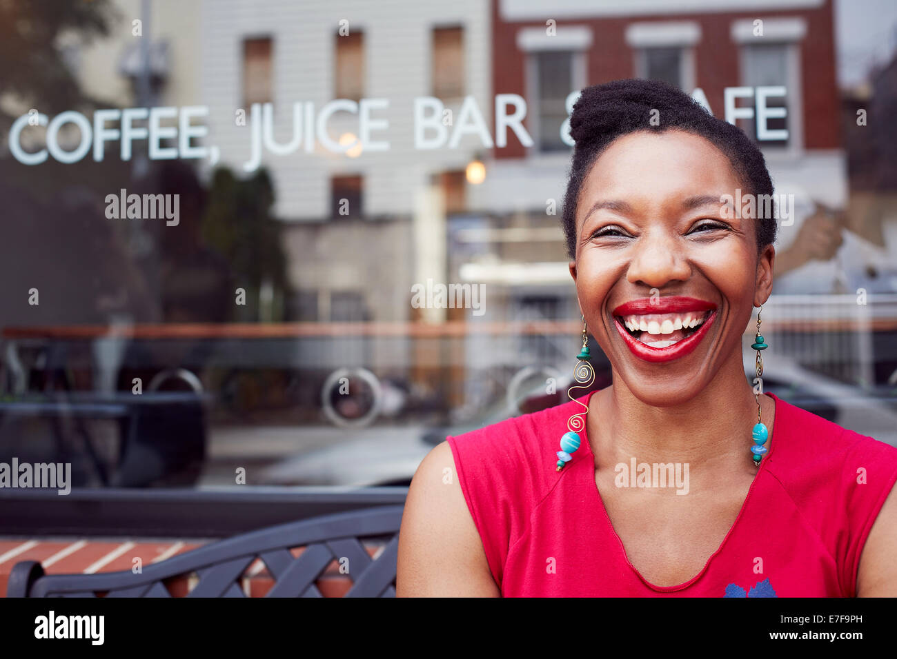 Woman laughing outside coffee shop on city street Stock Photo