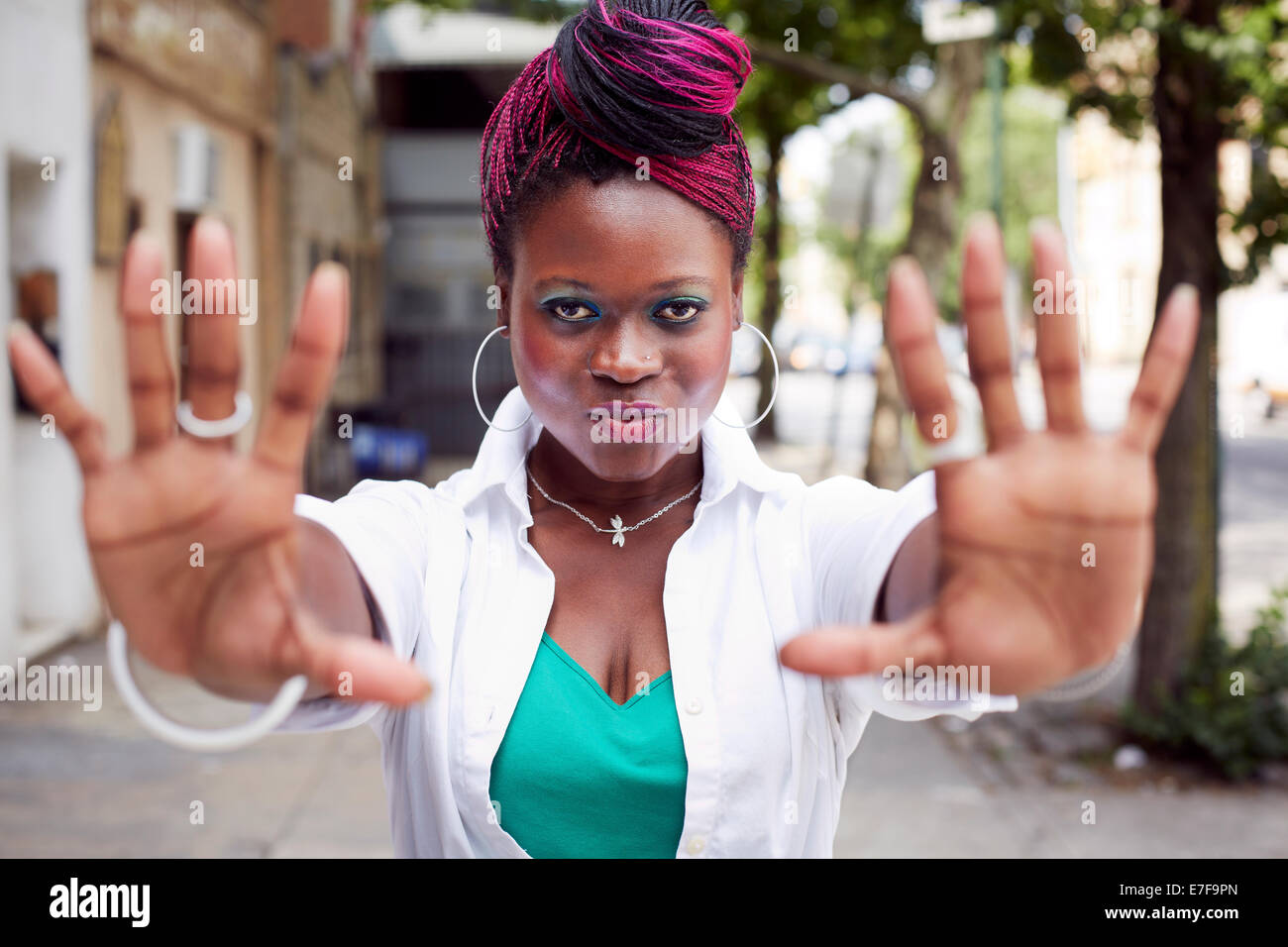 Woman holding out hands on city street Stock Photo