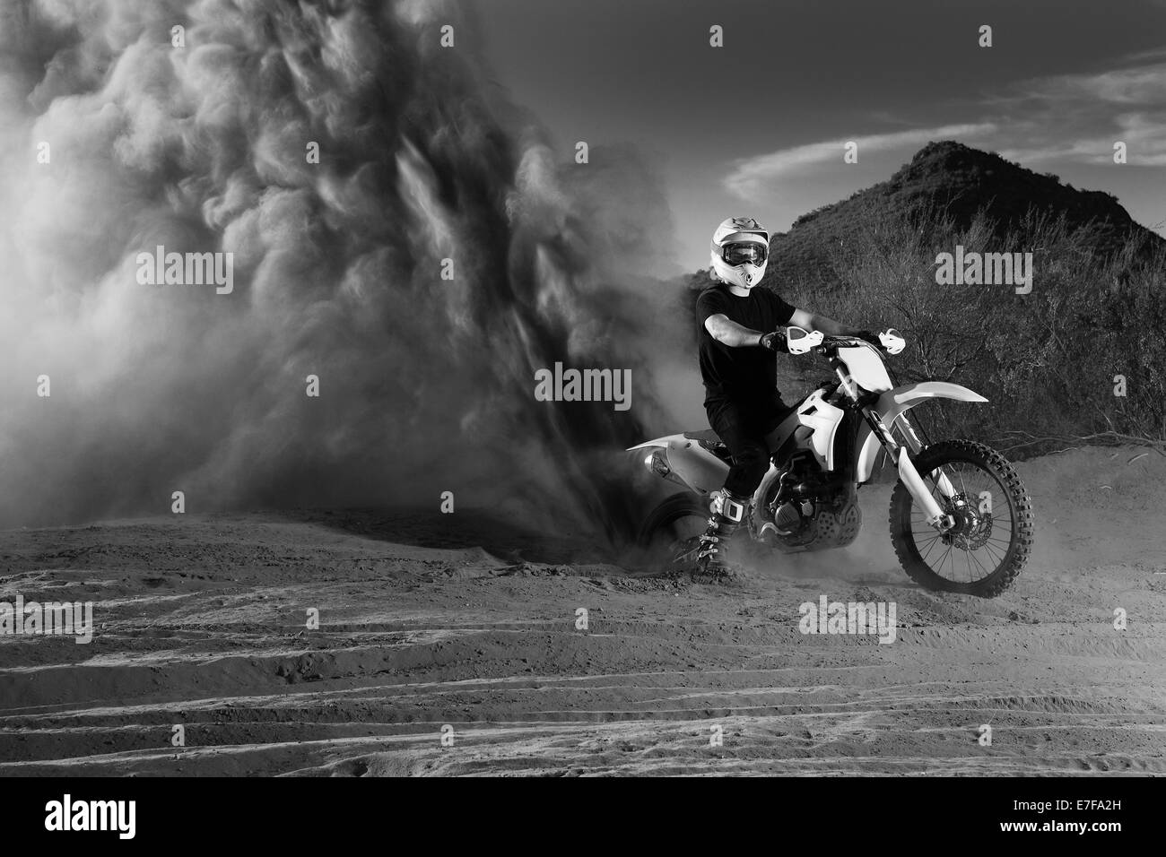 Caucasian man riding dirt bike in dust cloud Stock Photo