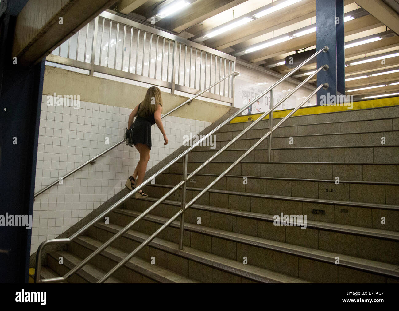 Woman climbs steps out of subway Stock Photo