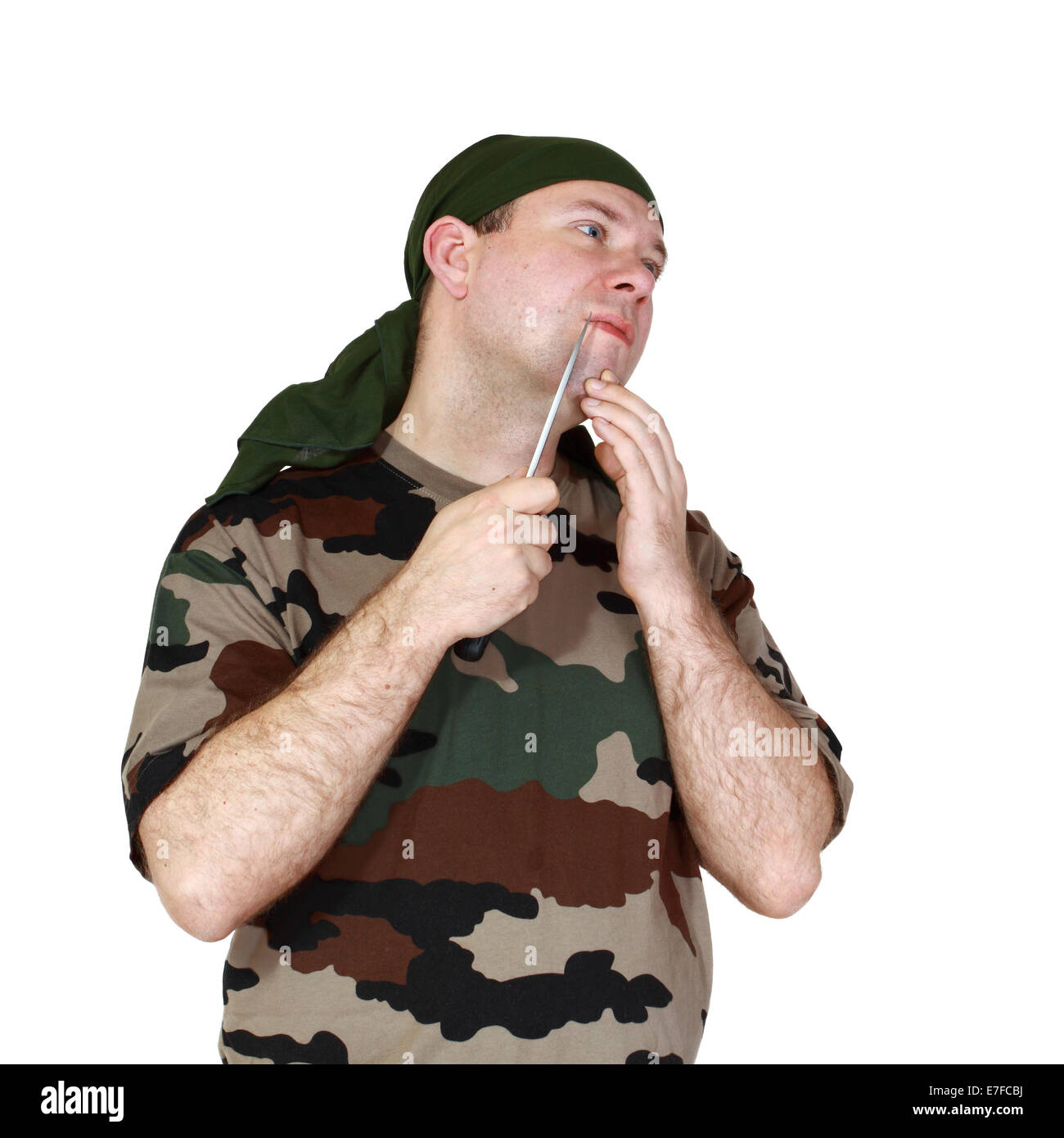 Man in camouflage shaves his face using a battle knife. Isolated on white background Stock Photo