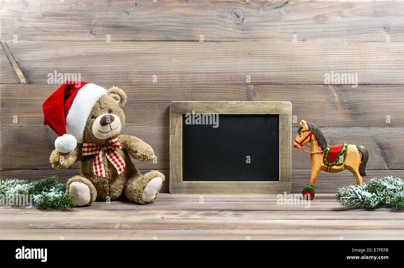 nostalgic christmas decoration with antique toys teddy bear and wooden rocking horse. vintage style picture with blackboard for Stock Photo