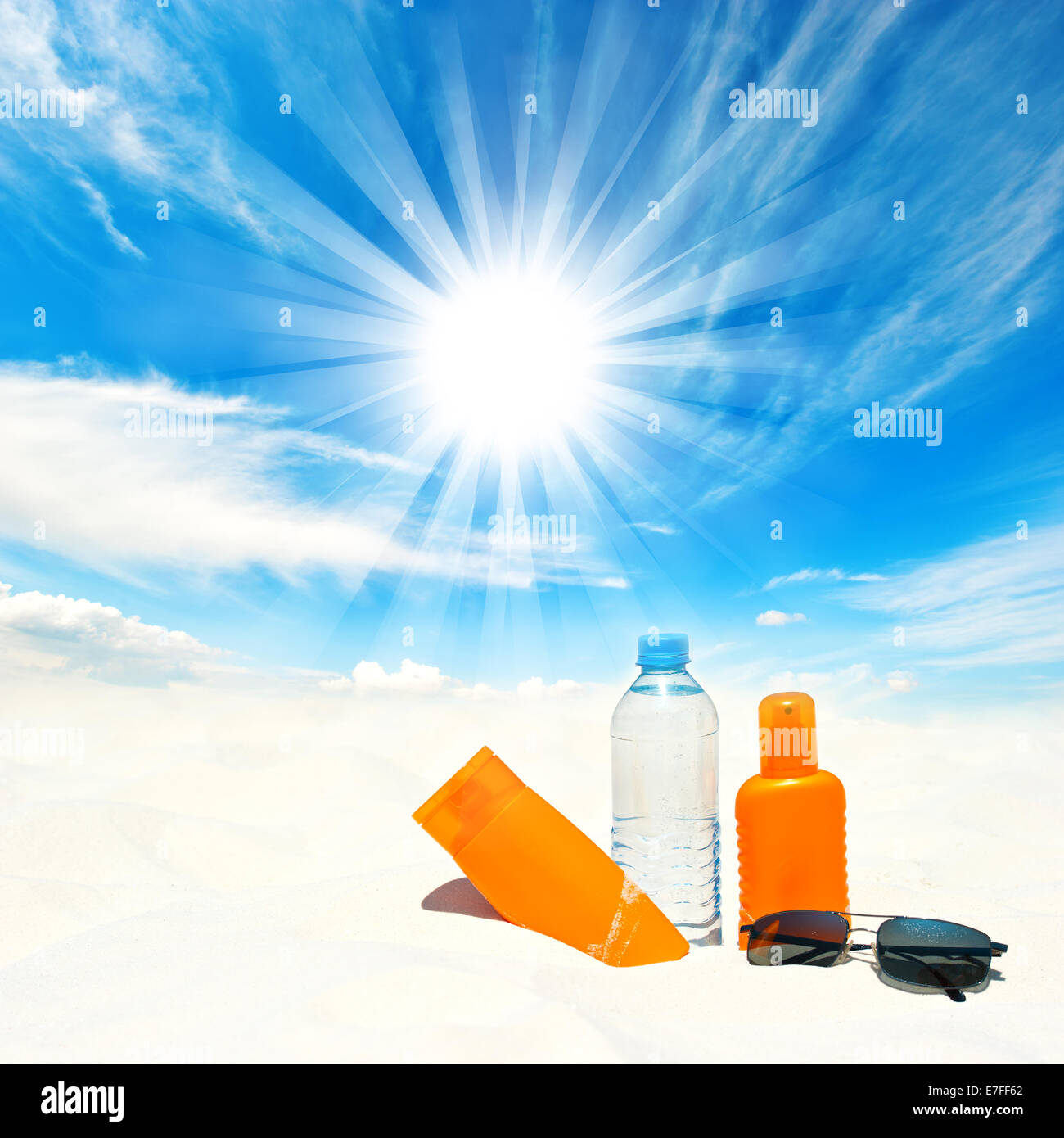 Sunscreen cream and bottle of water over sunny blue sky background. Sun protection concept Stock Photo