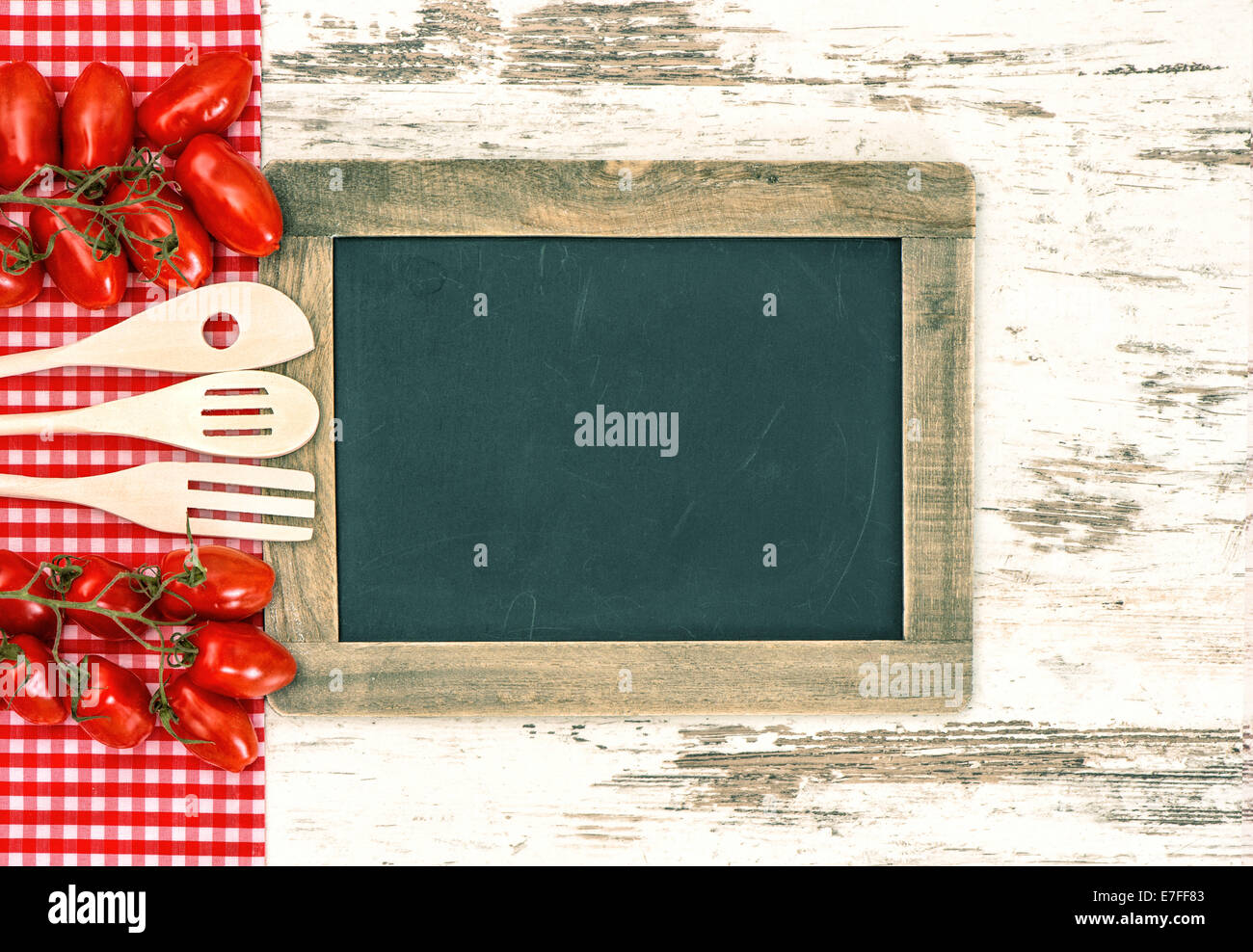 Wooden kitchen utensils with red tomatoes and blackboard for your text Stock Photo
