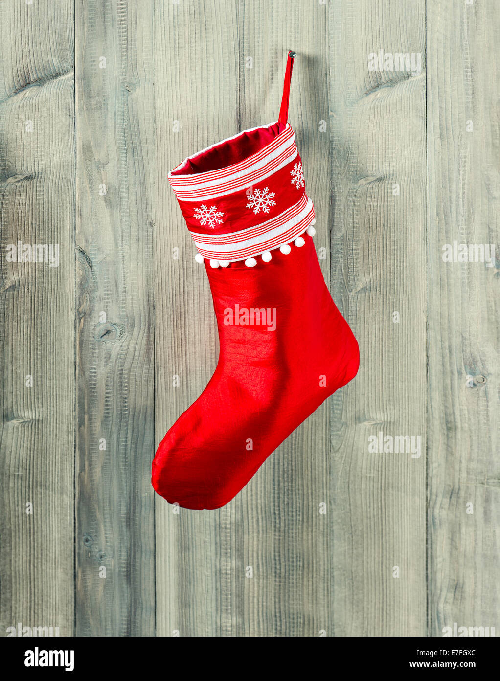 christmas stocking. red sock with snowflakes for Santas gifts hanging over rustic wooden background Stock Photo