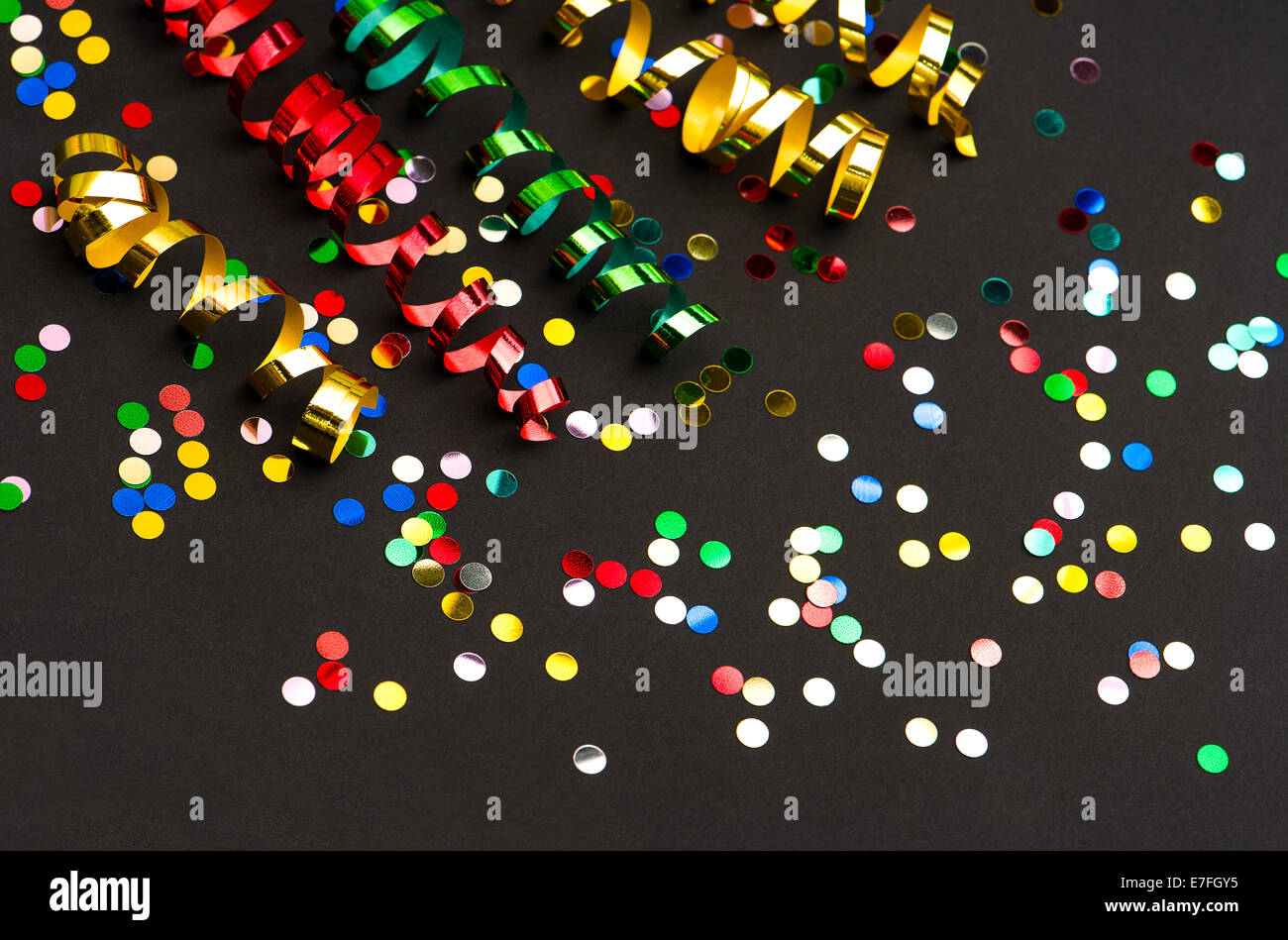 colorful streamer and confetti on black paper background. party decoration Stock Photo