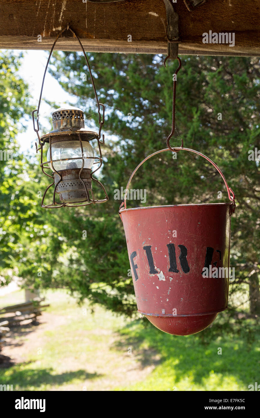 Old worn fire bucket and oil lamp hanging from rafters of log cabin Stock Photo