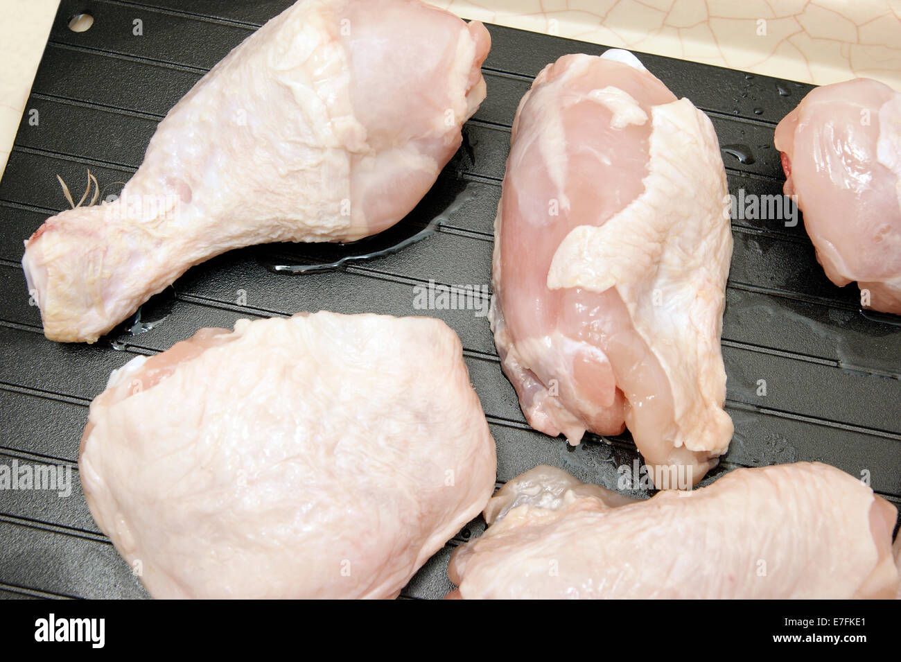Defrosting chicken legs & thighs on a super defrost tray to speed up the natural process therefore bringing them to room temperature more quickly. Stock Photo