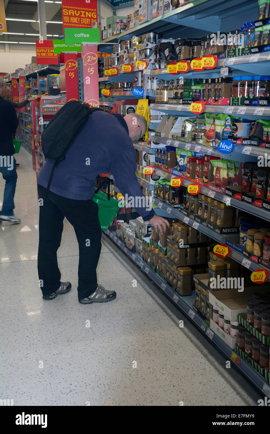 A man selecting the 'own brand' of coffee in an Asda store. Stock Photo