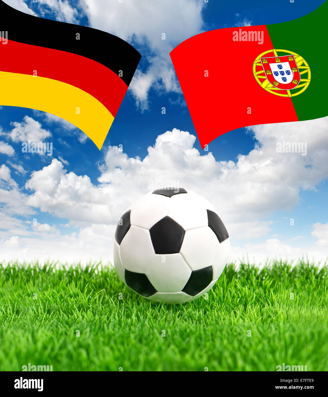 soccer ball on green grass and naional flags of germany and portugal over dramatic blue sky Stock Photo