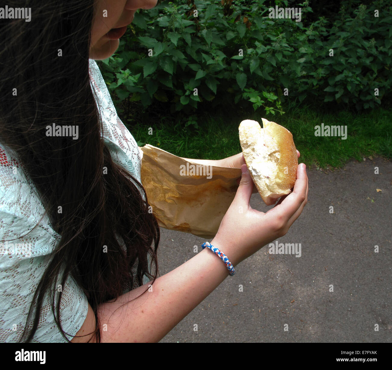 Young girl eating filled roll outside Stock Photo