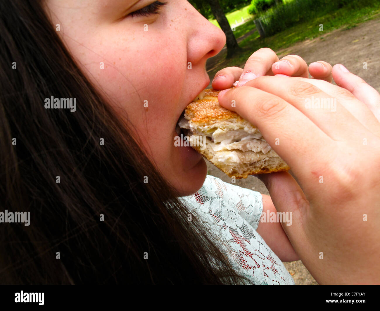 Young girl eating filled roll outside Stock Photo