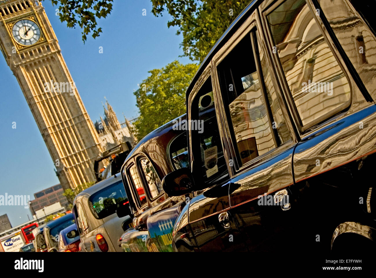 Iconic London taxi cabs approach Big Ben and Parliament Square, Westminster, London. Big Ben is currently undergoing restoration. Stock Photo