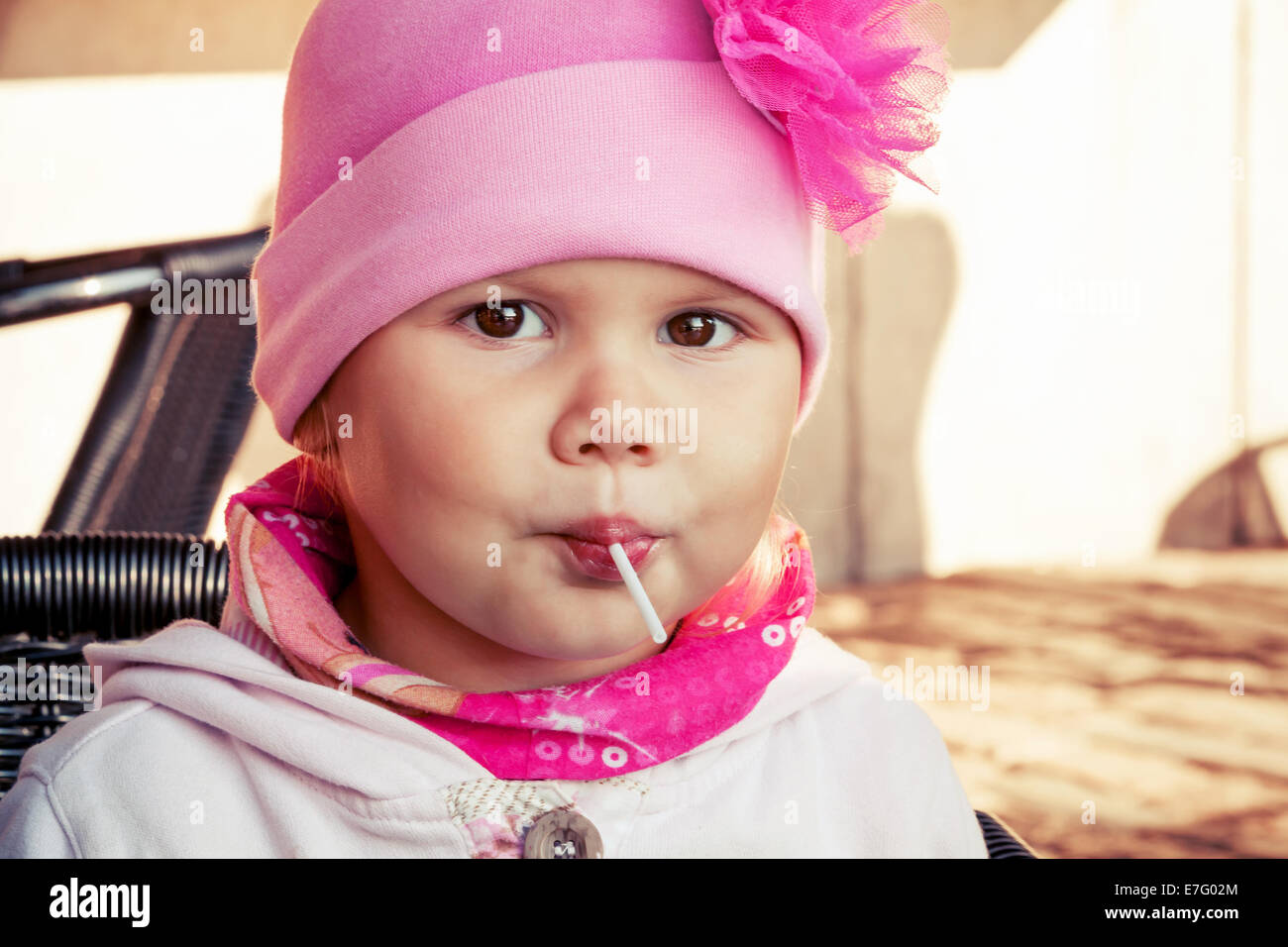 Closeup portrait of baby girl in pink eating lollipop Stock Photo