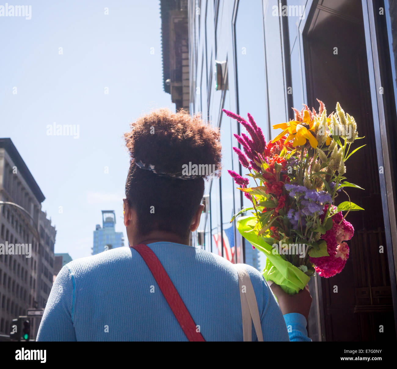 A woman walks with a bouquet of flowers in Midtown Manhattan in New ...