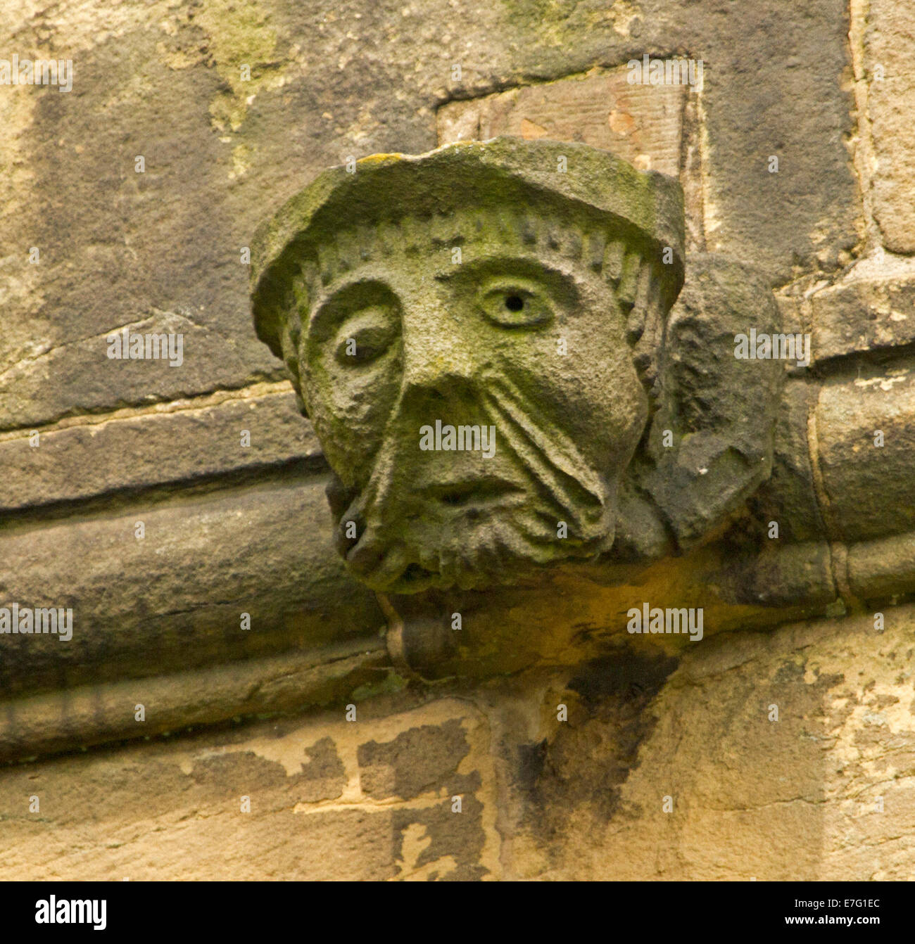 Ancient stone gargoyle of human face on high wall of church at English ...