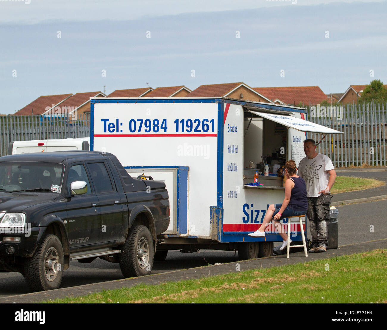 Man and woman, one seated on stool, waiting to be served at mobile roadside takeaway food van in England Stock Photo