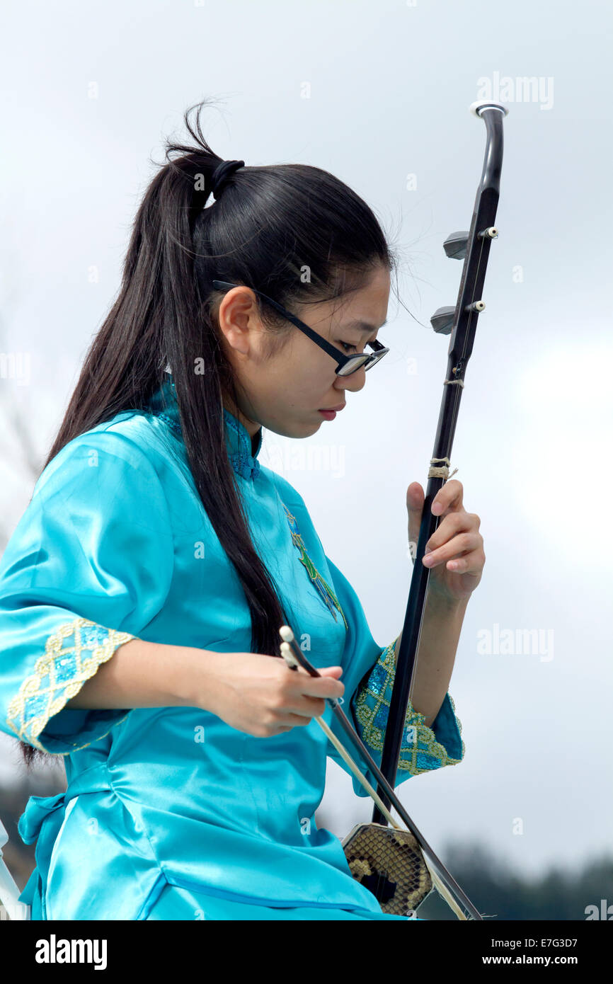 Young lady in a blue dress playing the Erhu, a Chinese classical instrument Stock Photo