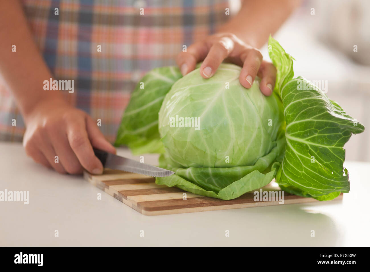 Green cabbage on cutting board in kitchen. Stock Photo
