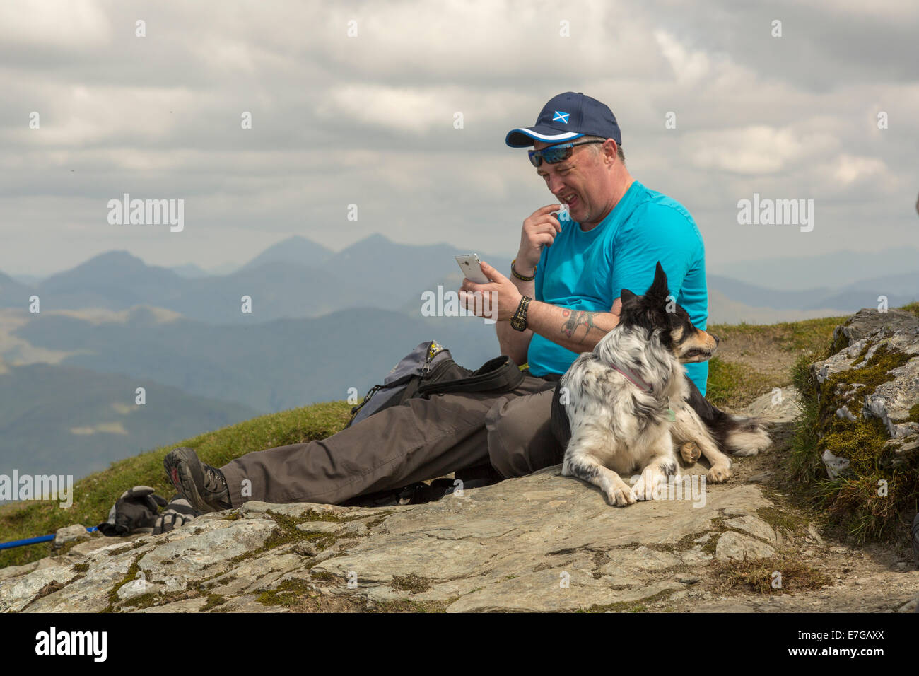 A man tries to get phone reception on the peak of Ben Lomond. Stock Photo