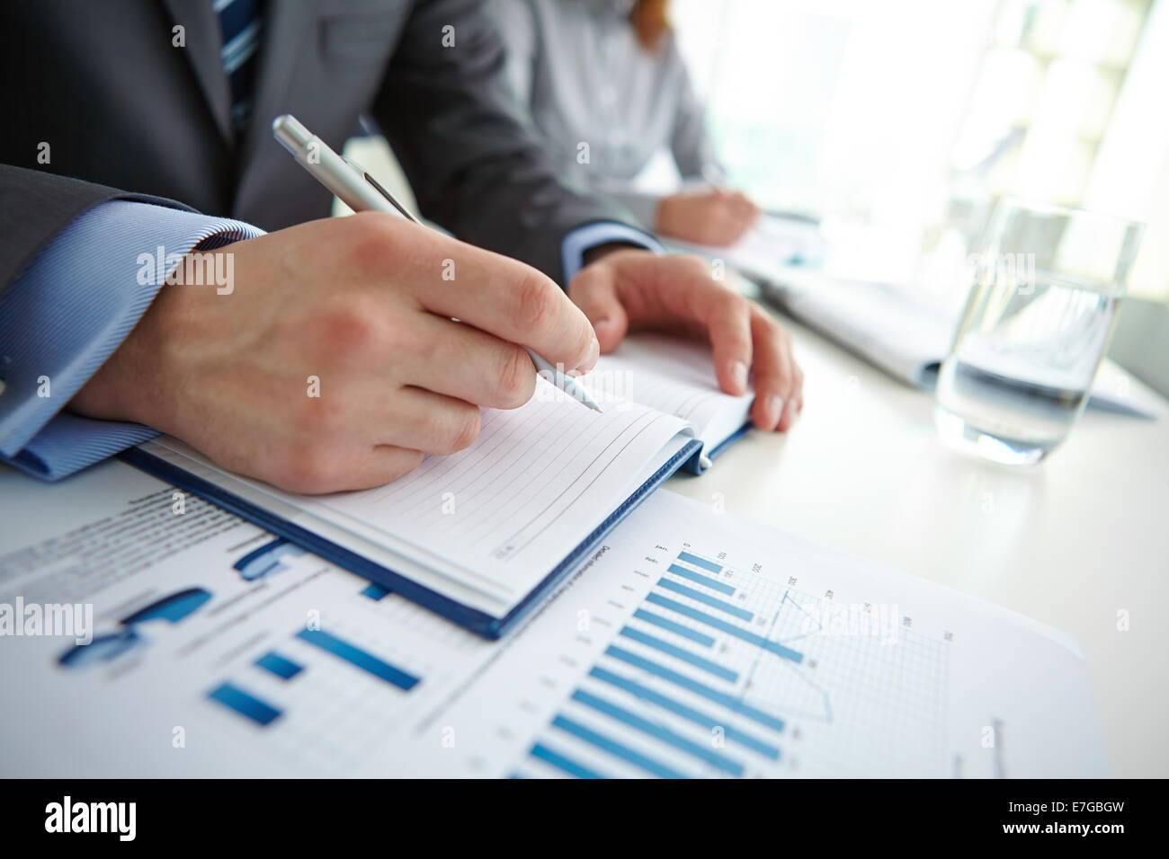 Male hand writing in notebook with female on background Stock Photo - Alamy