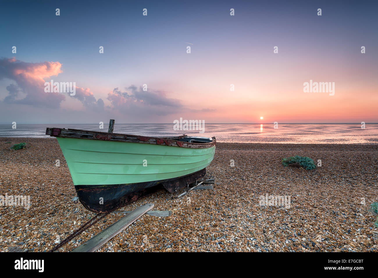 Green fishing boat at sunrise on a shingle beach at Lydd on Sea in Kent Stock Photo