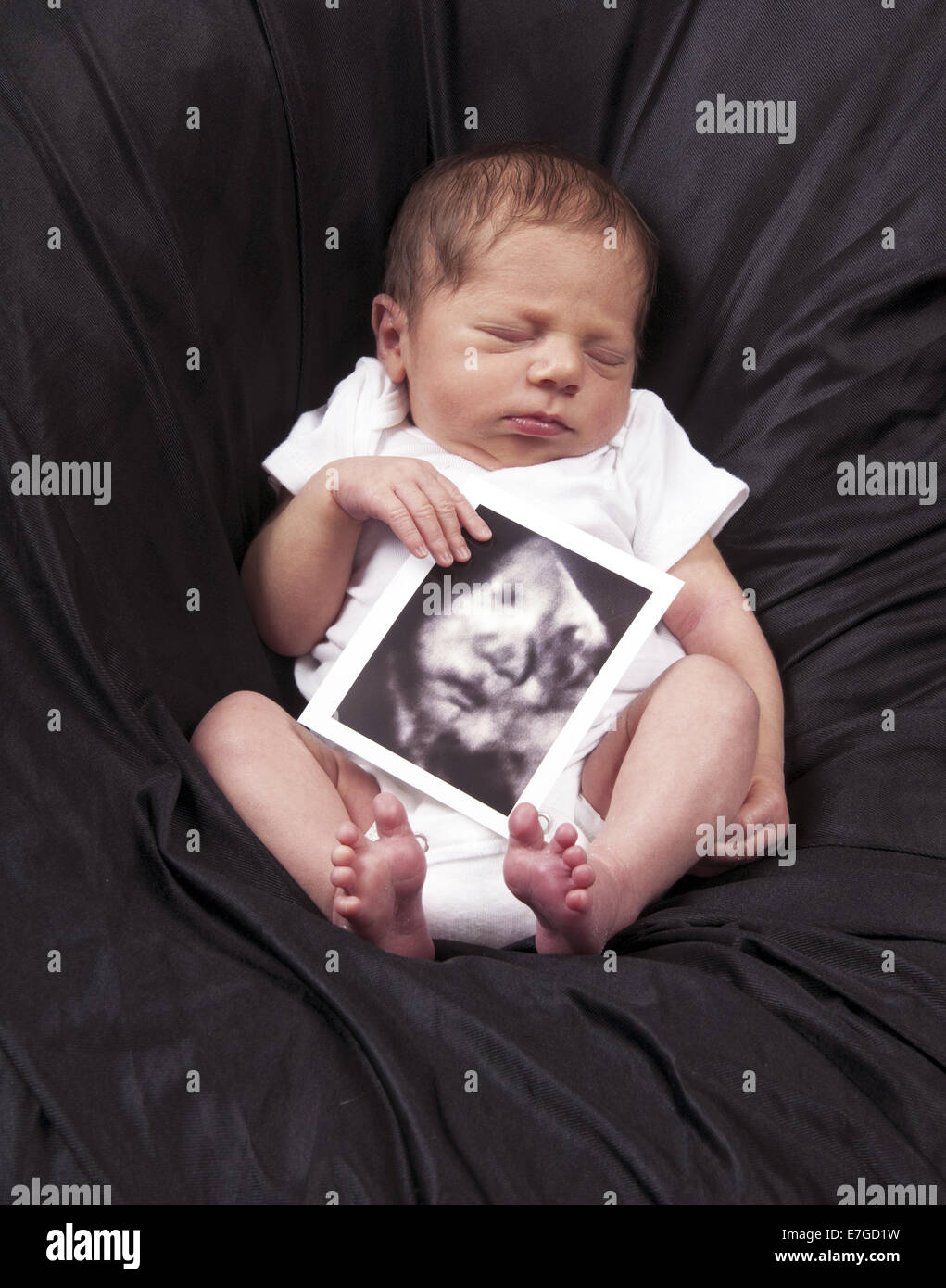 Newborn boy sleeping holding an ultrasound picture of himself. Clermont Florida USA Stock Photo