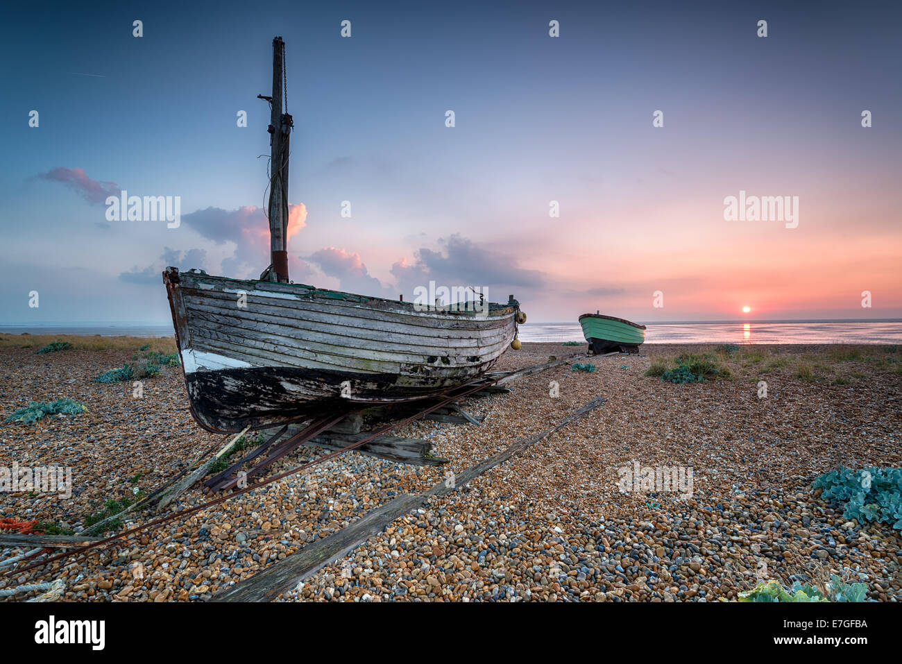 Beautiful sunrise over old wooden boats on a shingle beach Stock Photo