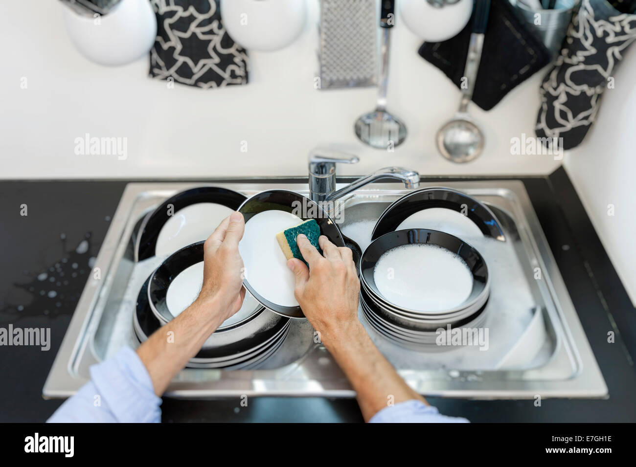 Man in kitchen who cleans the dishes Stock Photo