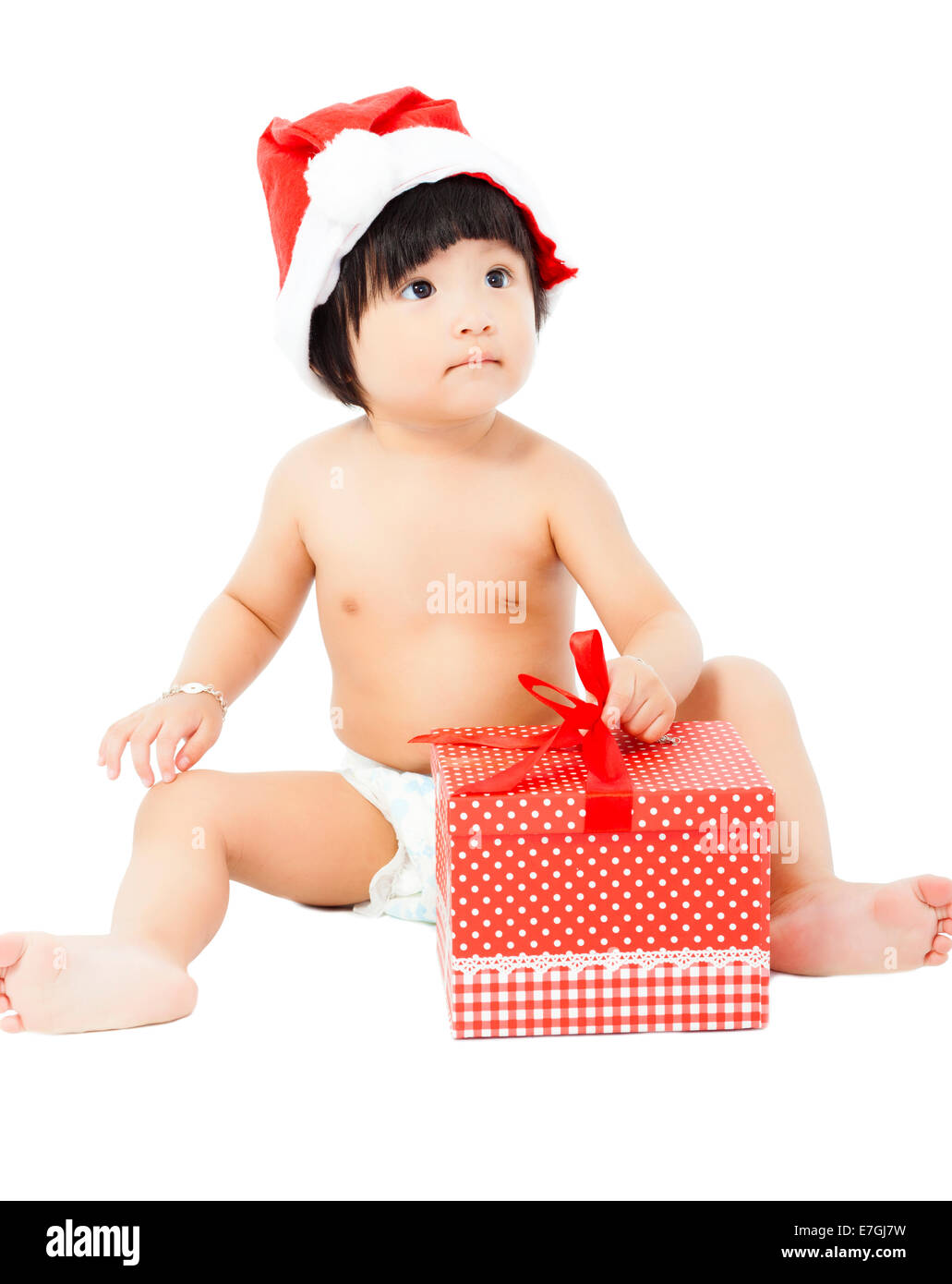 adorable baby in Santa cap sitting on floor with christmas gift Stock Photo