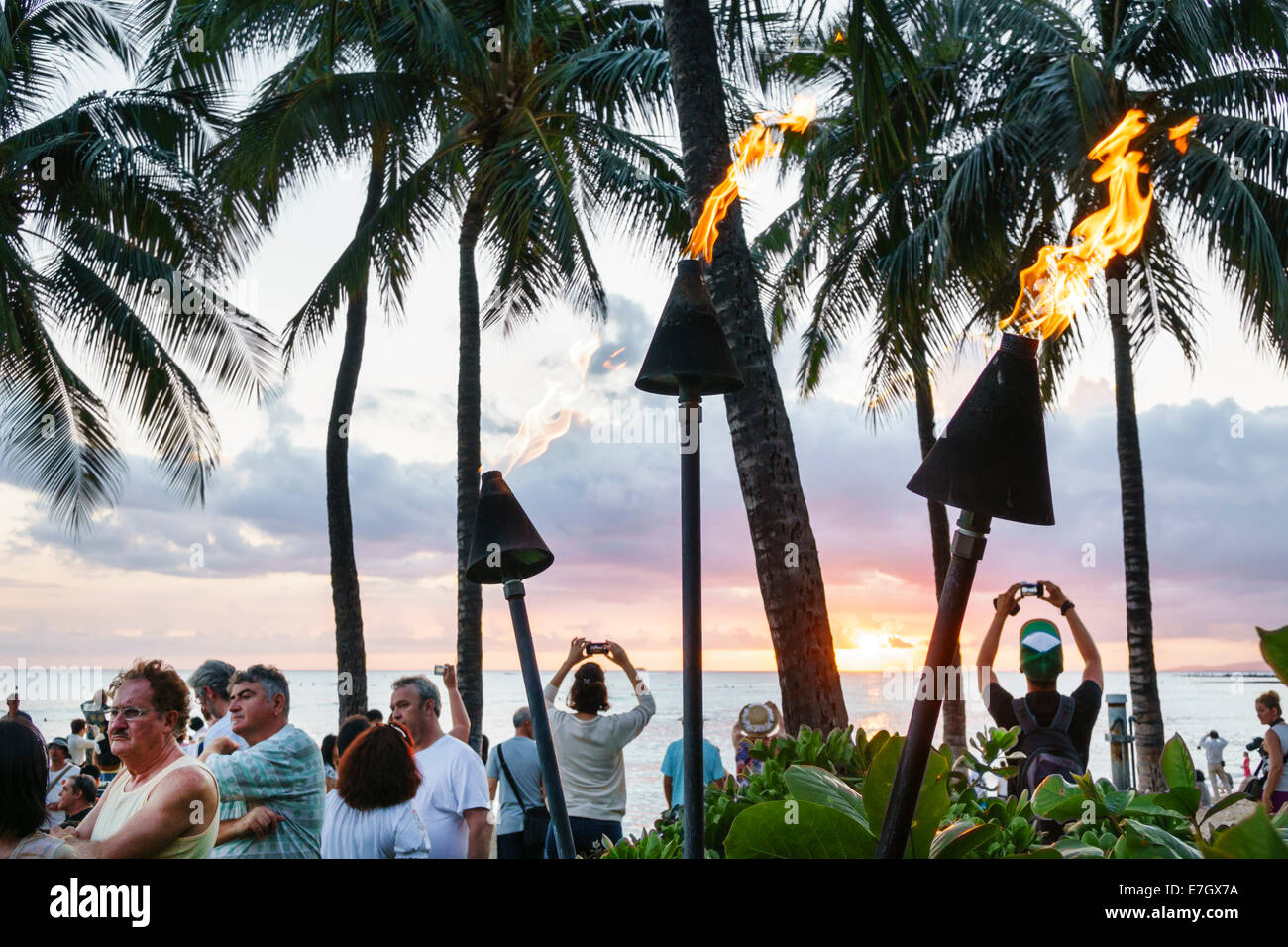Hawaii,Hawaiian,Honolulu,Waikiki Beach,Kuhio Beach Park,Pacific Ocean,sunset,Waikiki Bay,palm trees,tiki lanterns,lit,fire,USA,US,United,States,Americ Stock Photo