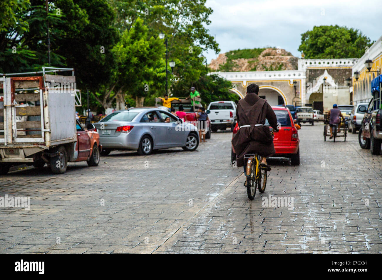 catholic monk riding a bicicle down old street in a small town in the yucatan Stock Photo