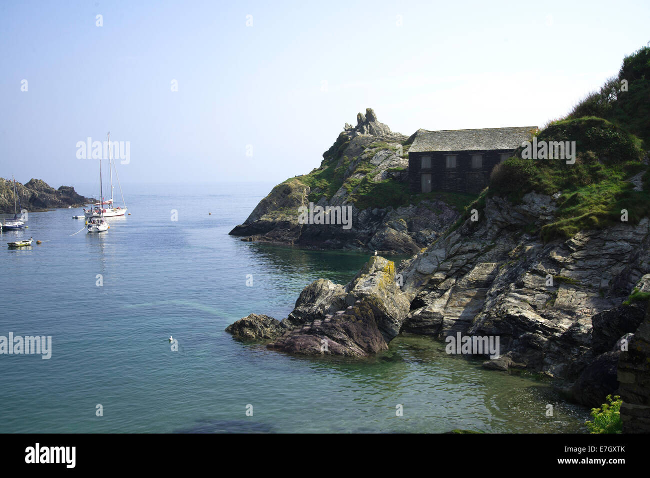 Harbour, (harbor) entrance with boats and remote building on rocky peninsular Stock Photo