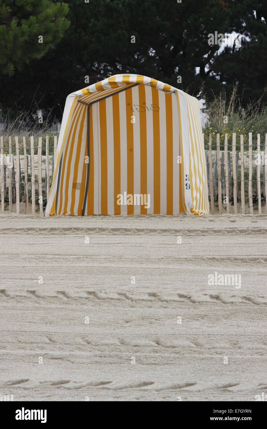 Beach hut at Carnac, Brittany/Bretagne, France. Yellow and white deckchair stripes. Tracks in sand. Stock Photo