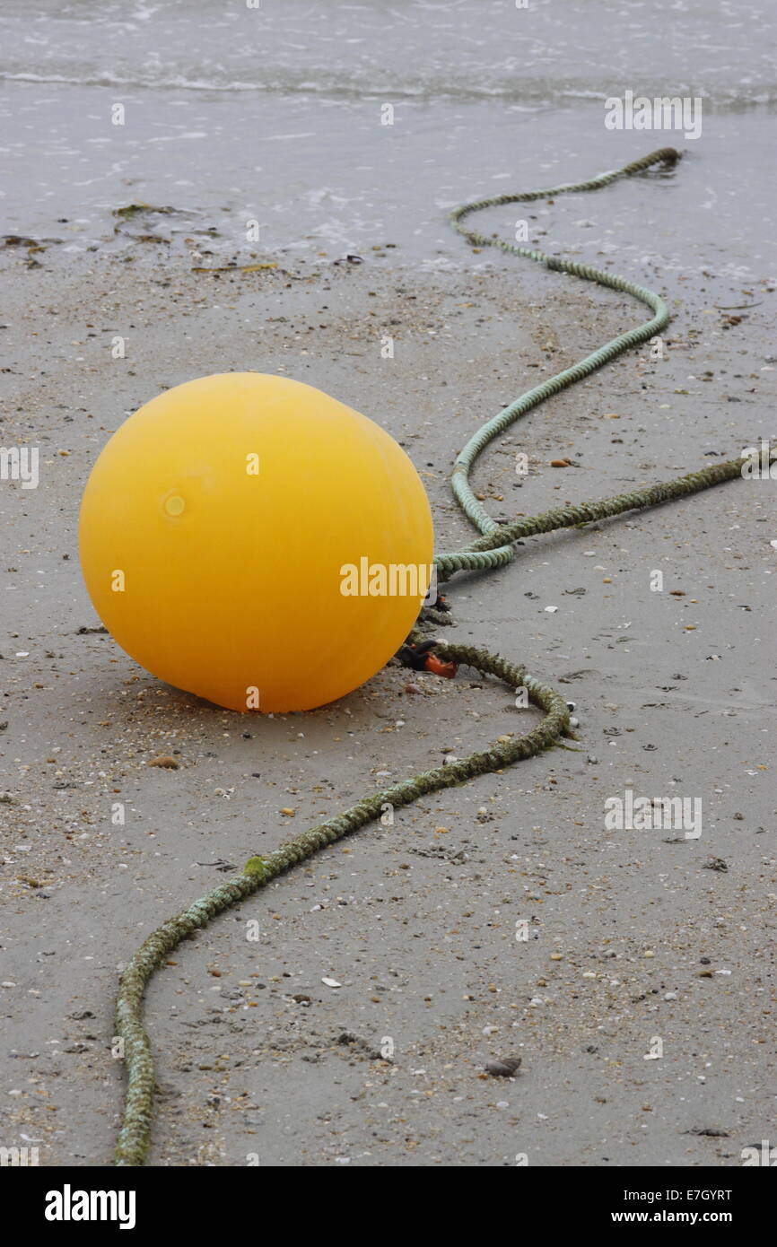 Beach at Carnac, Brittany/Bretagne, France with yellow ball shaped float and ropes. Stock Photo