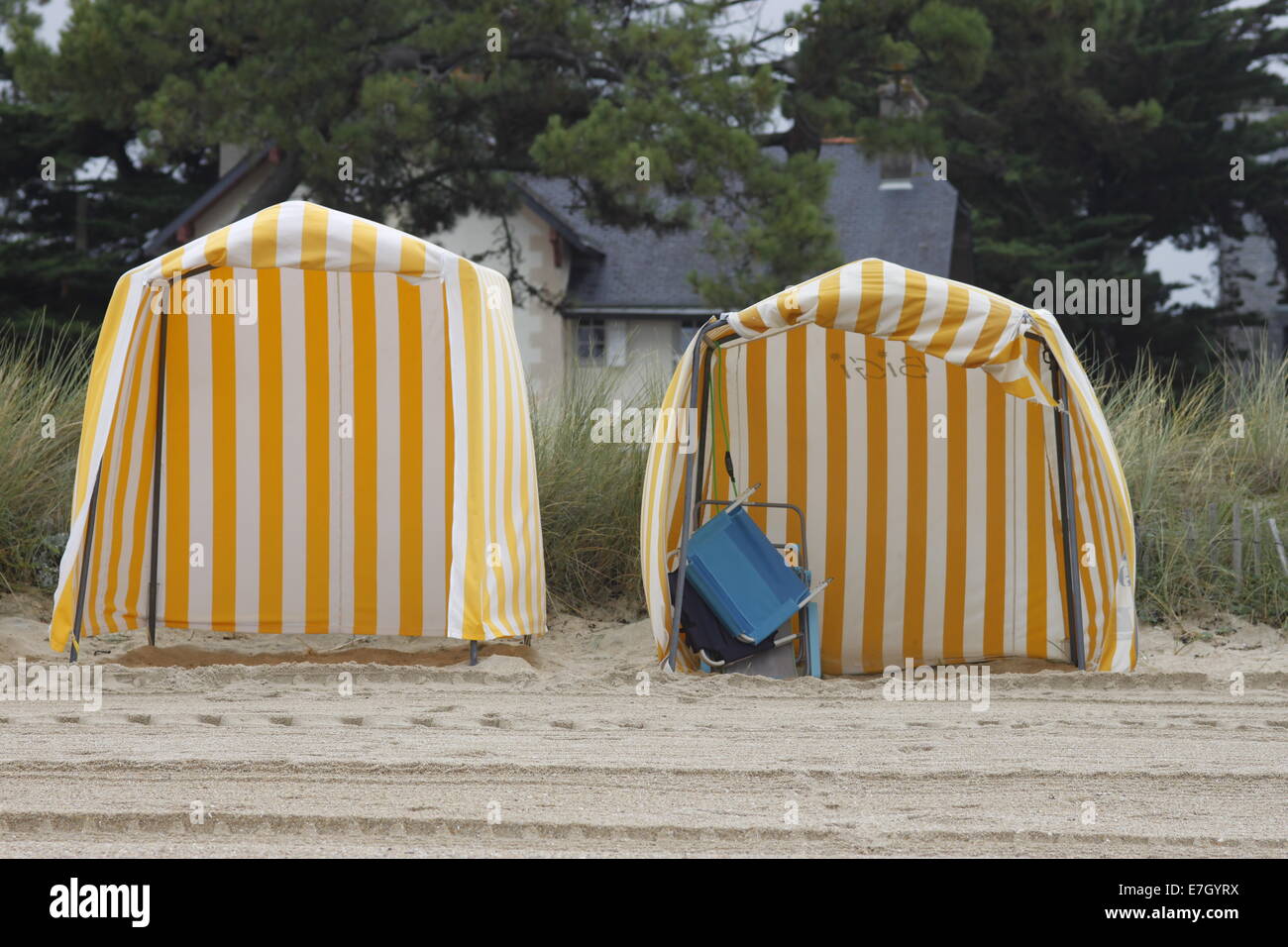 Beach huts at Carnac, Brittany/Bretagne, France. Yellow and white deckchair stripes. Tracks in sand. Stock Photo