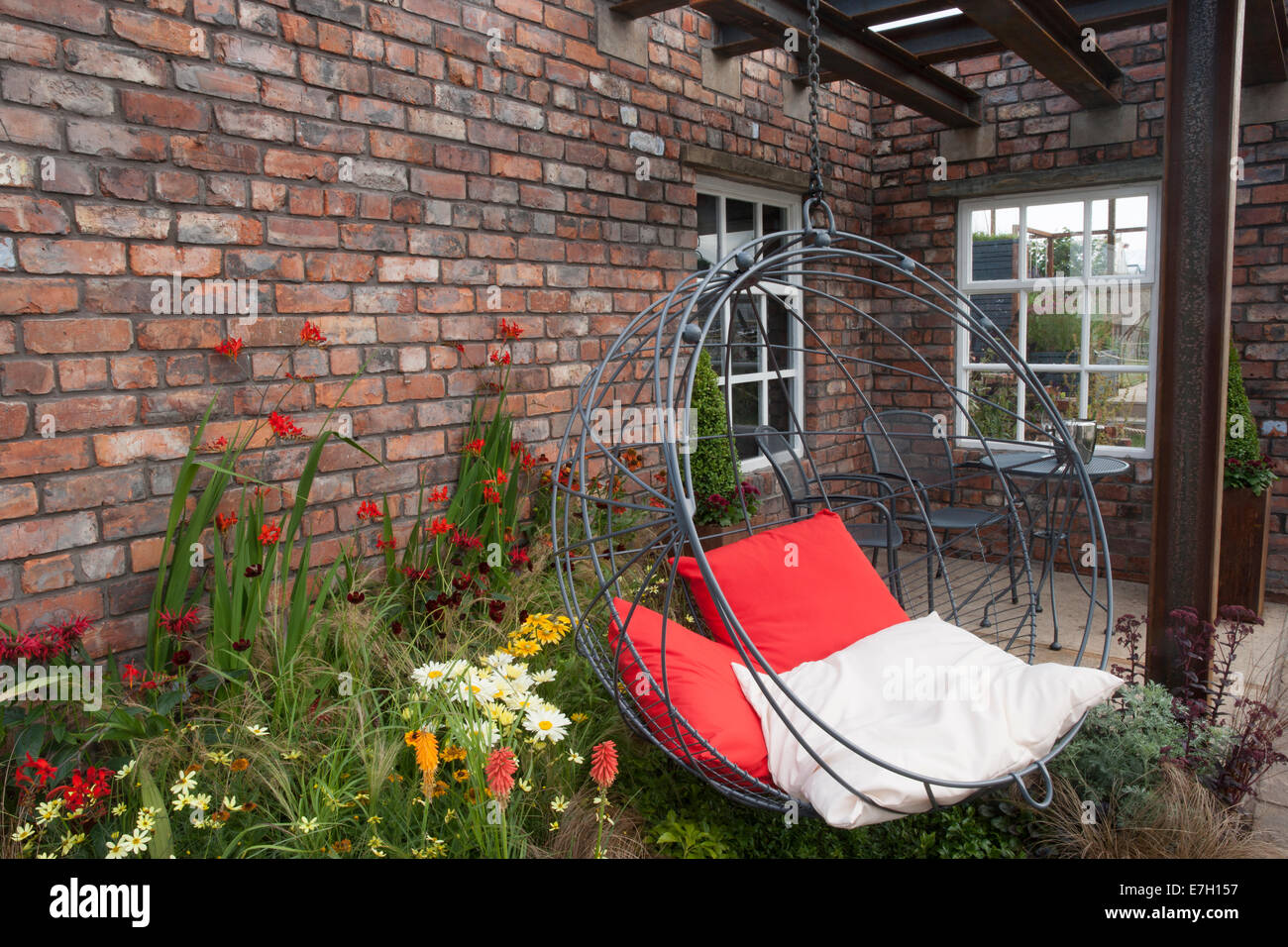 Garden - Industrial Transitions - swing seat in outdoor living area planting of Crocosmia 'Lucifer' Helenium an Stock Photo
