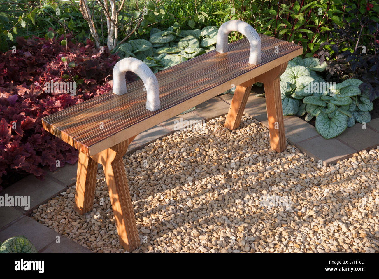 Garden with a wooden bench seat seating area on a gravel patio UK summer Stock Photo