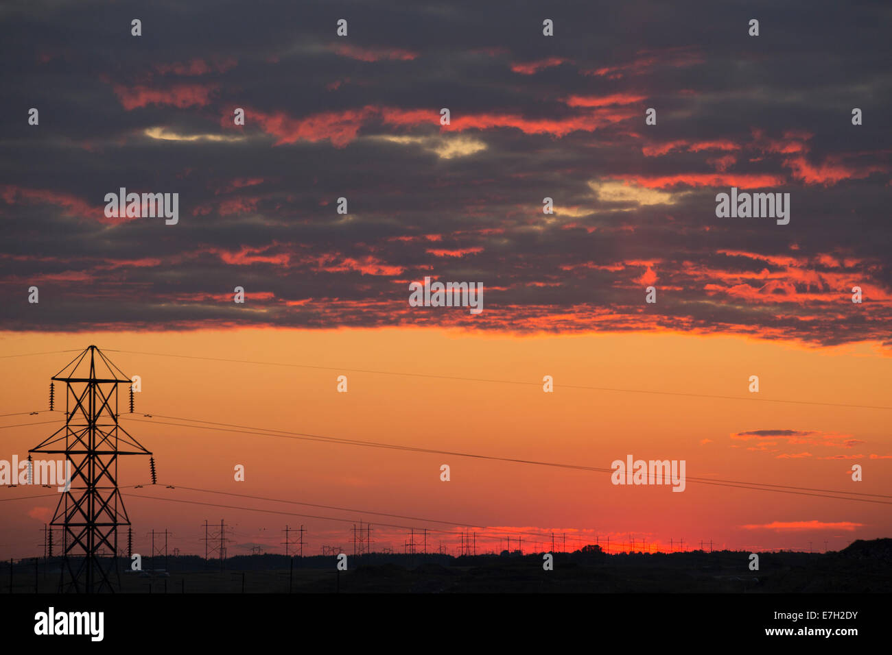 Transmission towers silhouetted against sunset sky Stock Photo - Alamy