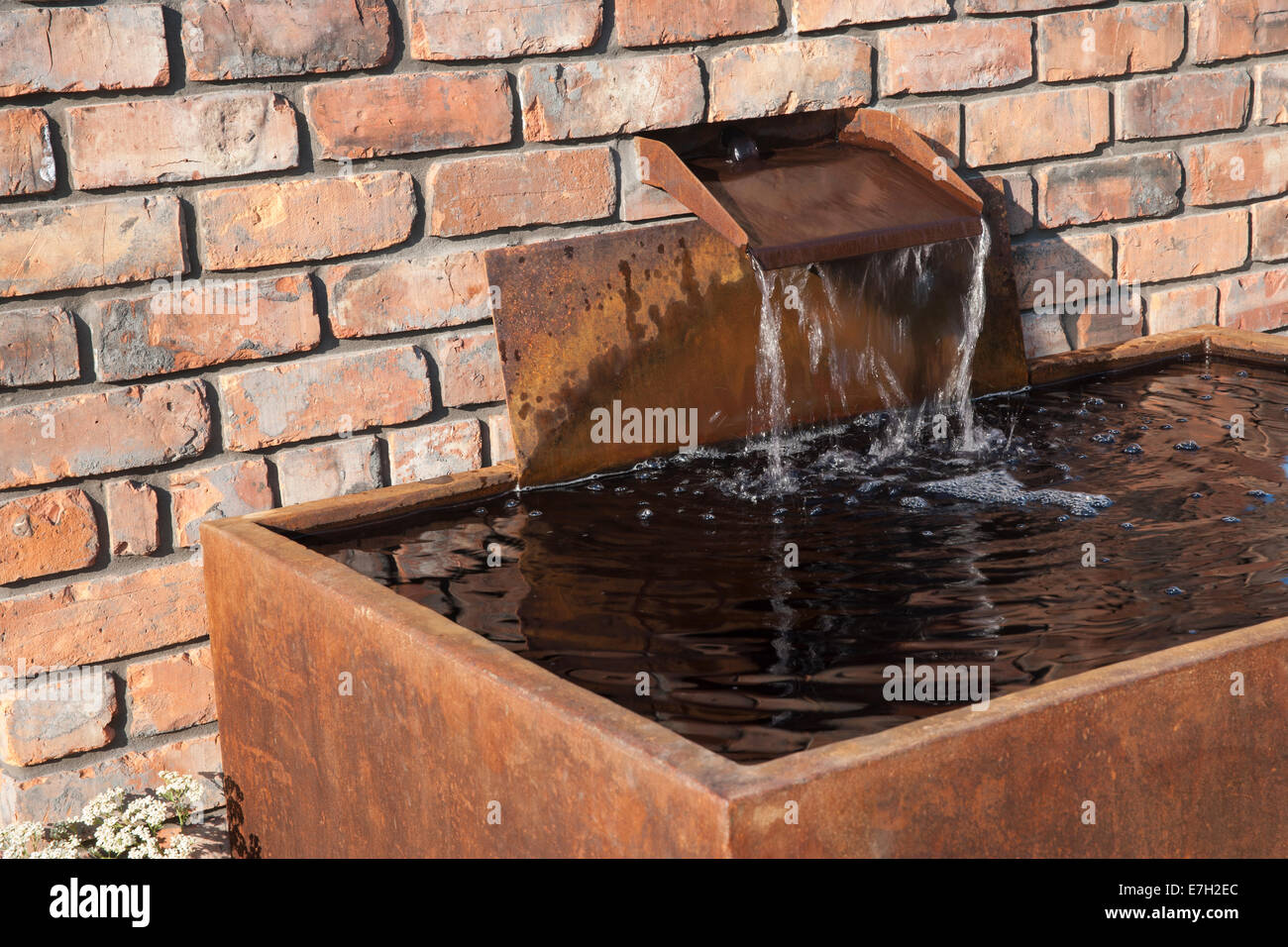 Garden - Industrial Transitions - water feature waterfall running into rusted water tank - Designer - Caroline Stock Photo