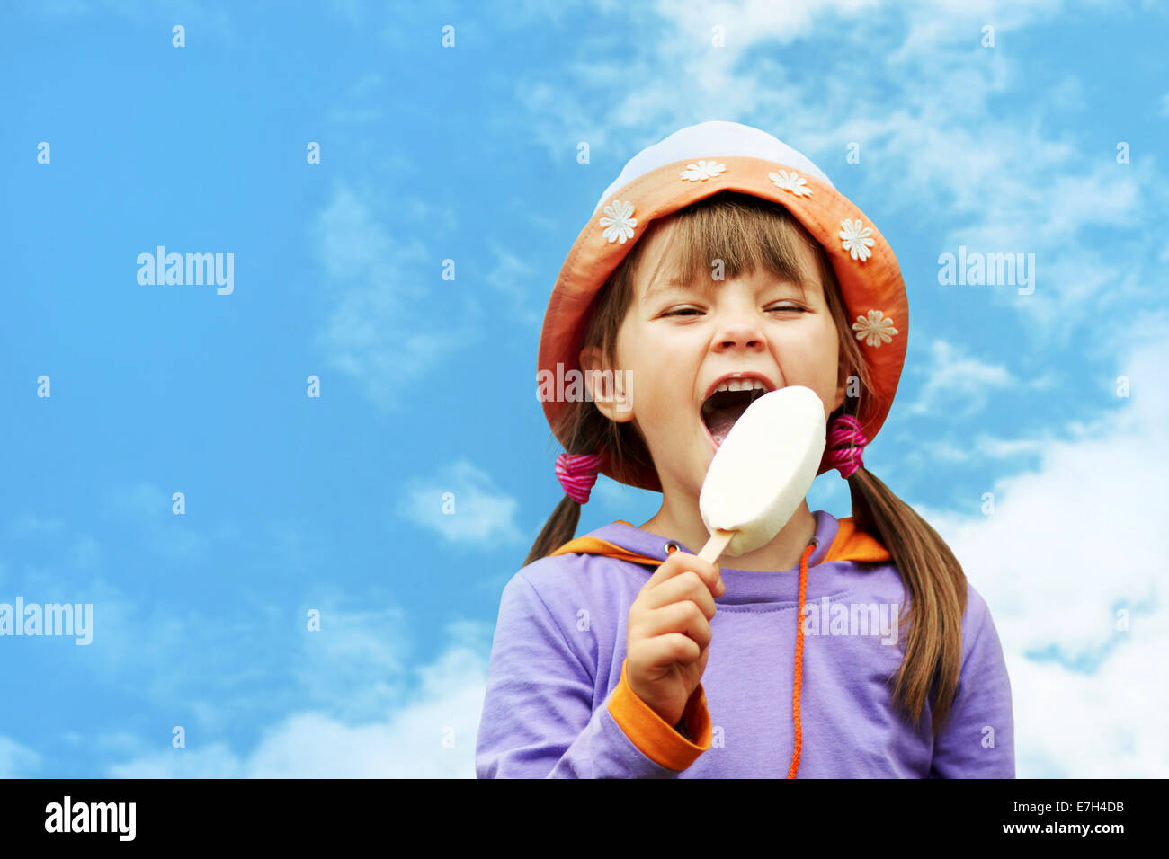 little girl in hat eating ice cream on a background of sky Stock Photo ...